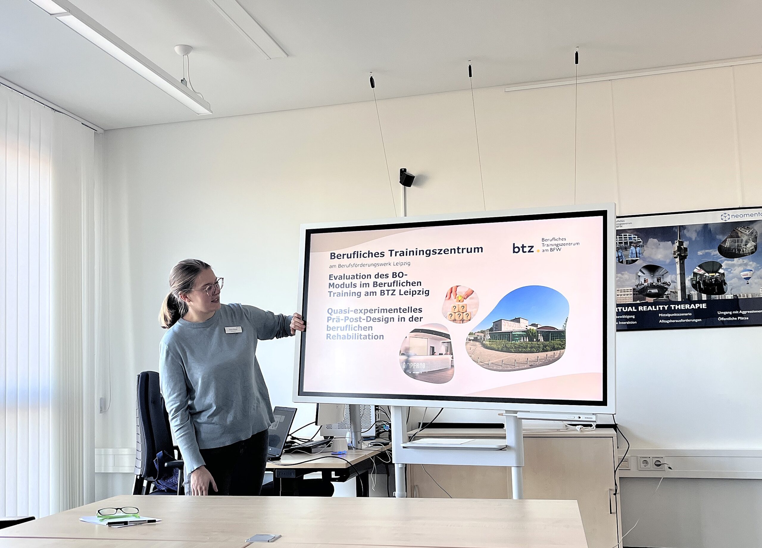 Junge Frau, Psychologin, stellt ihre Analyse über einen Monitor Mitarbeitenden des Beruflichen Trainingszentrums vor