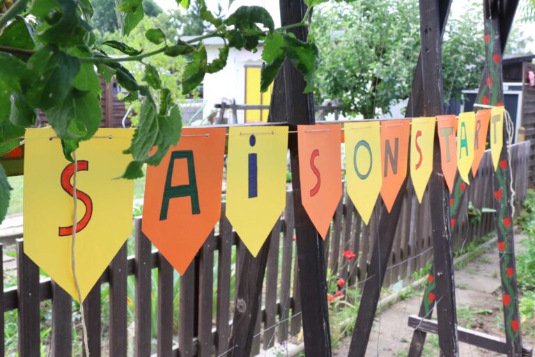 Gartenzaun mit Wimpeln mit der Aufschrift Saisonstart