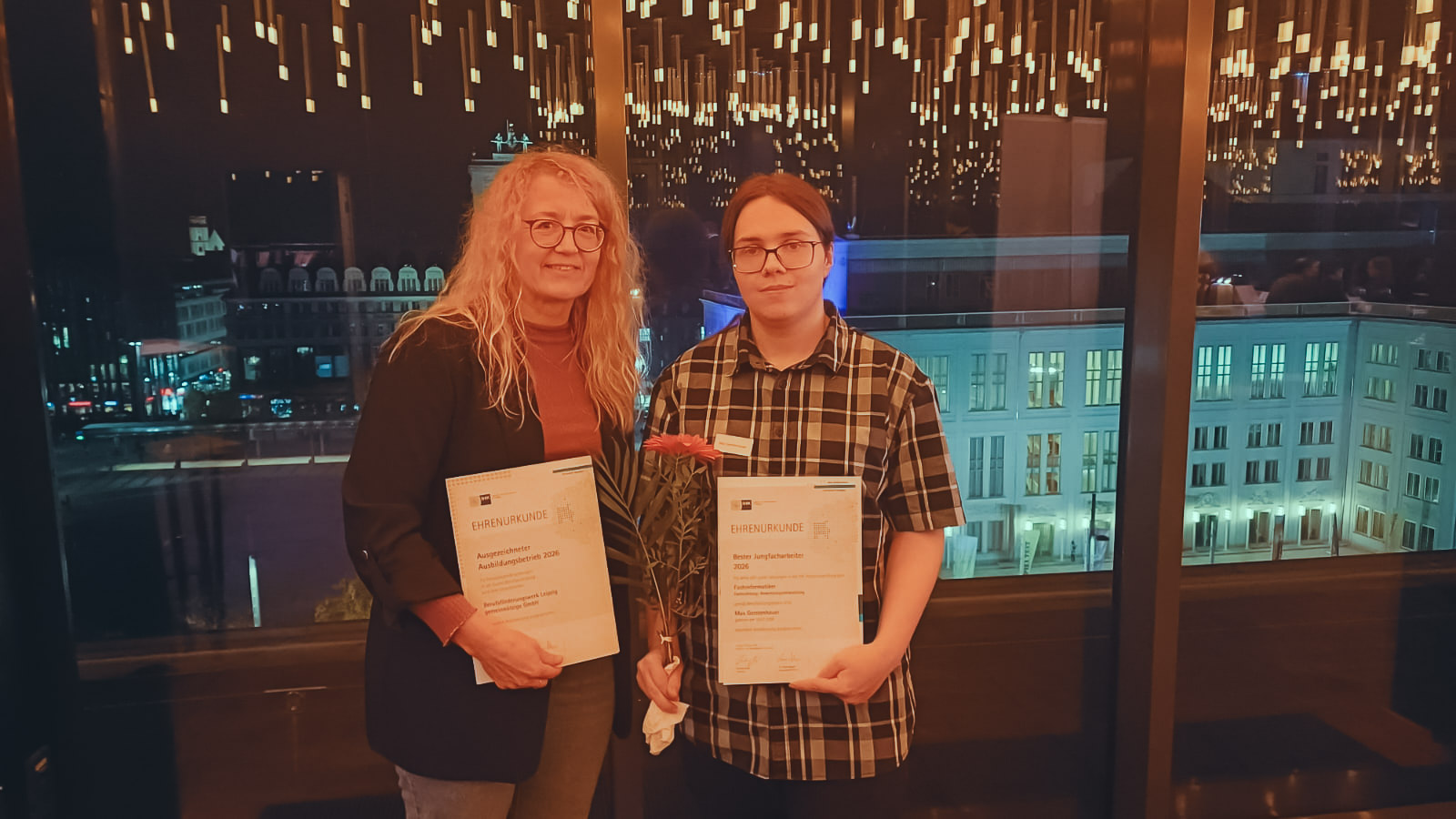 Ausbilderin mit der Urkunde für das BTZ am BFW, und IngE-Absolvent halten ihre Ehrenurkunden in den Händen.